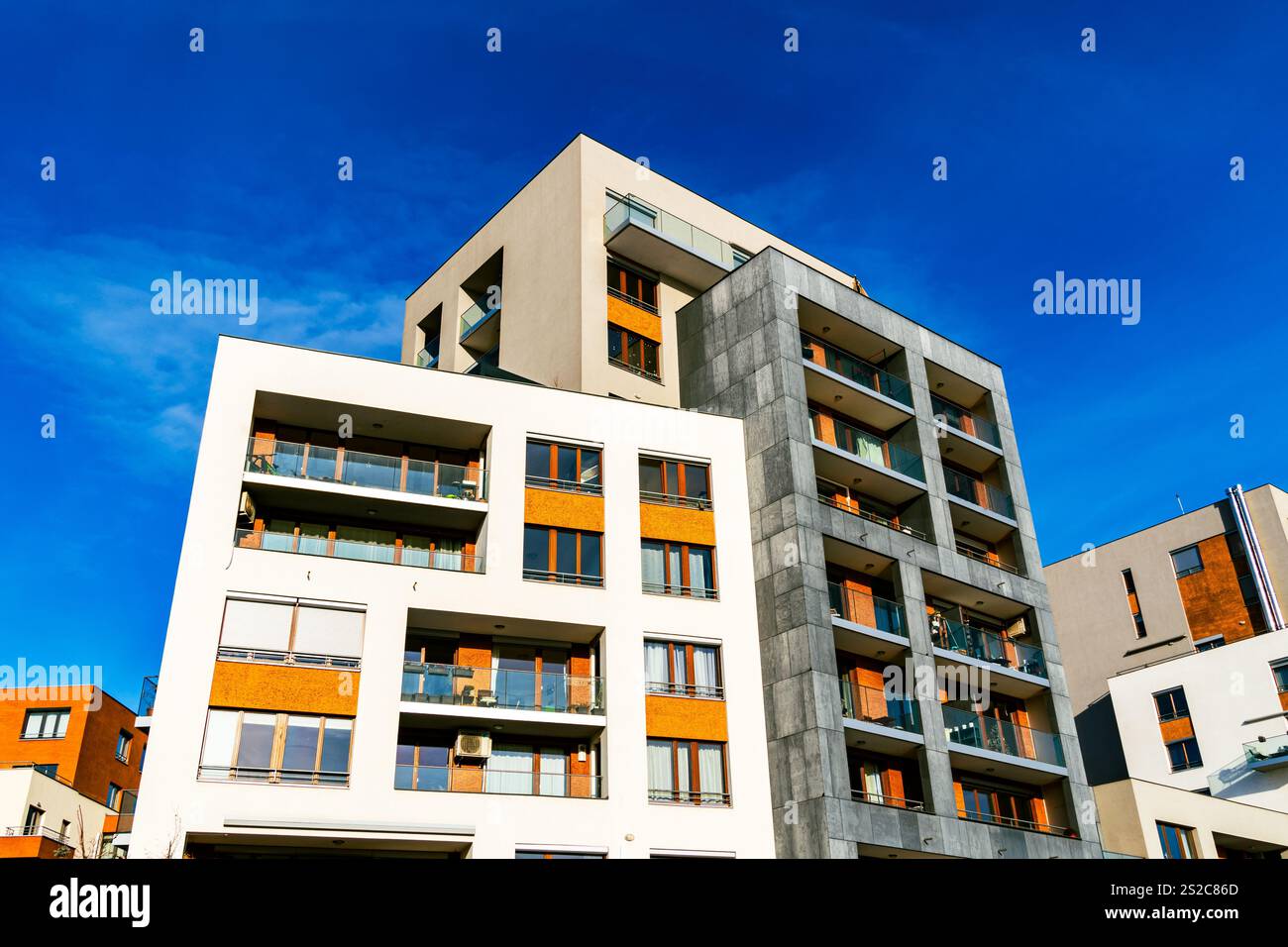 Moderno edificio residenziale a più piani con facciata vivace, grandi balconi e skyline urbano sotto il cielo azzurro Foto Stock