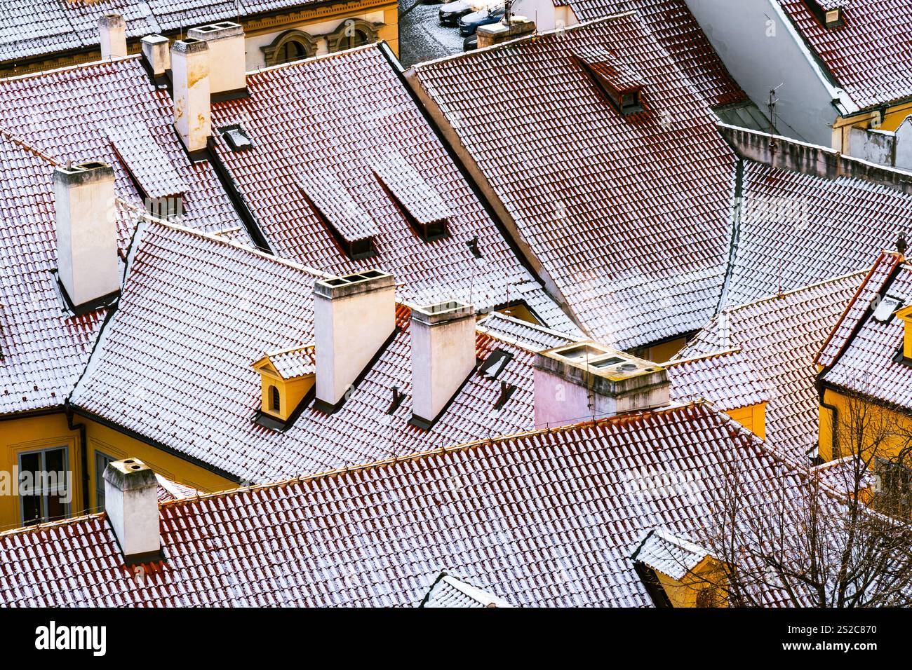 Tetti innevati di Malá strana a Praga con architettura storica e tetti di tegole rosse Foto Stock