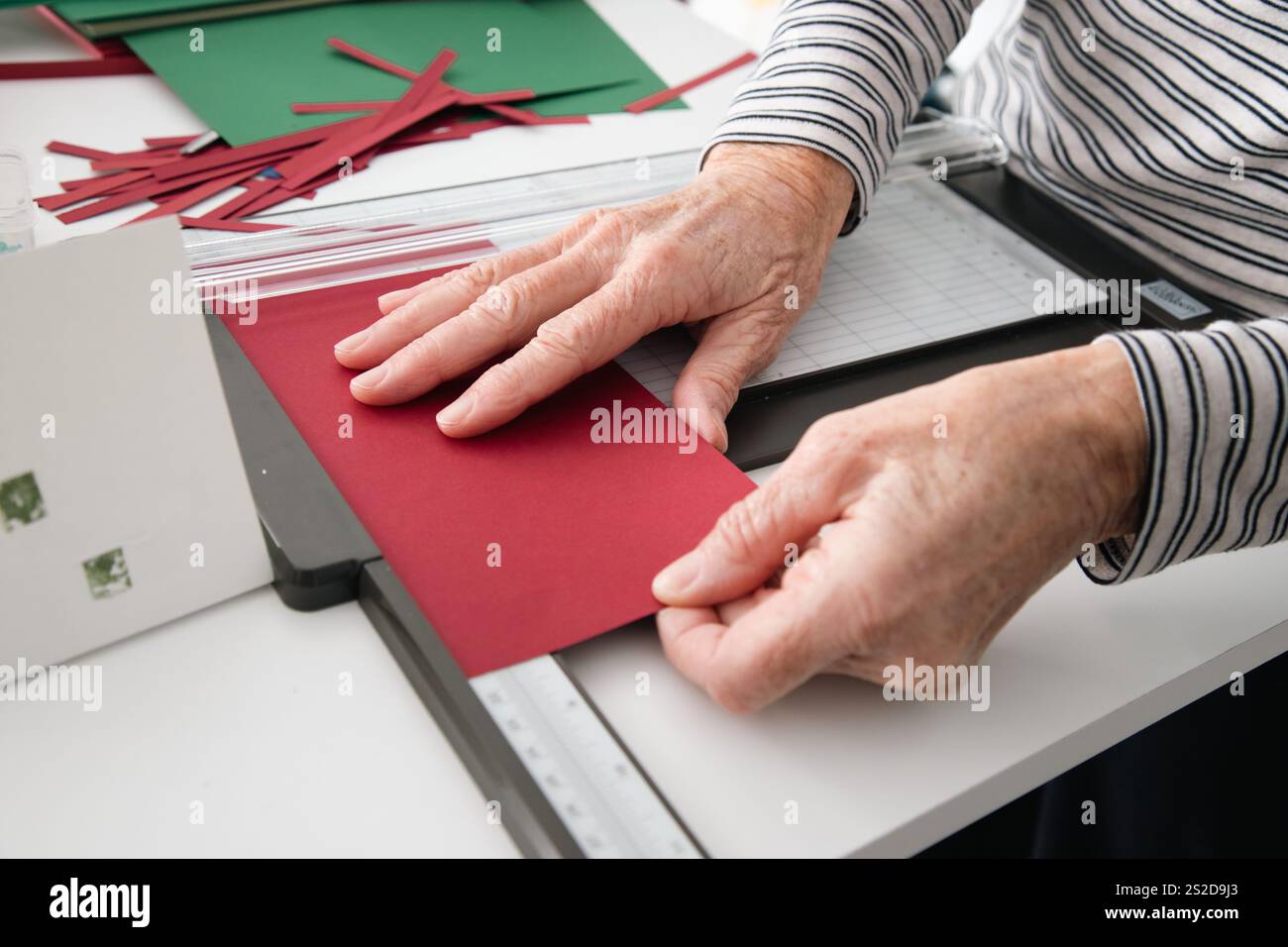 Primo piano di una donna seduta a un tavolo che prepara cartoline di Natale fatte in casa Foto Stock