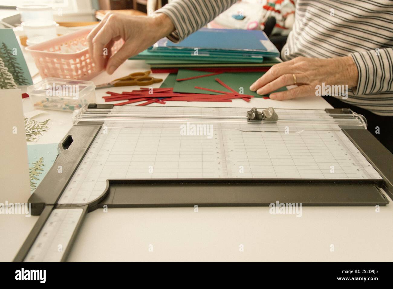 Primo piano di una donna seduta a un tavolo che prepara cartoline di Natale fatte in casa Foto Stock