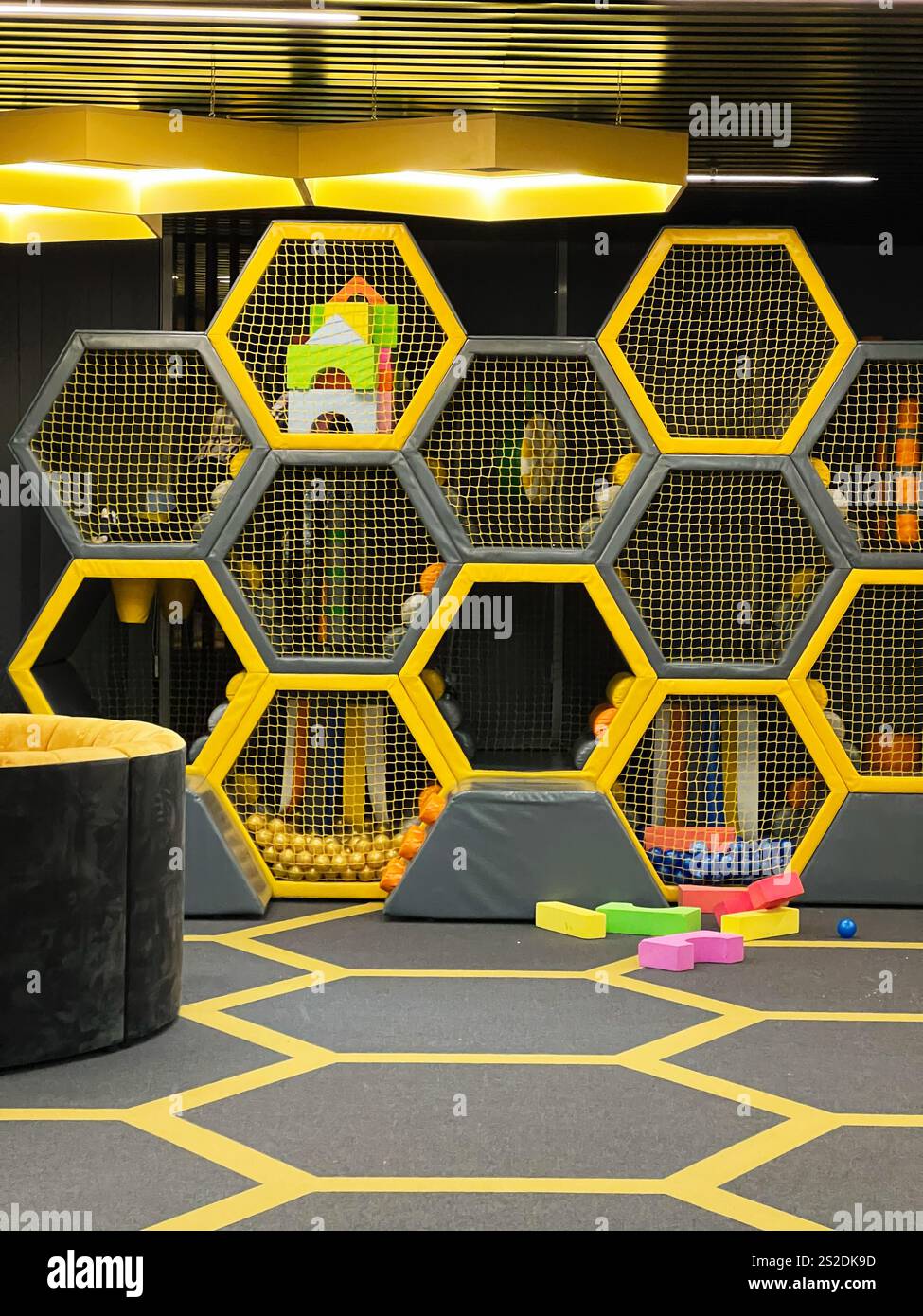 Un parco giochi interno elegante e vivace con strutture di gioco esagonali, elementi colorati e design interattivo. Perfetto per i bambini da spiegare Foto Stock