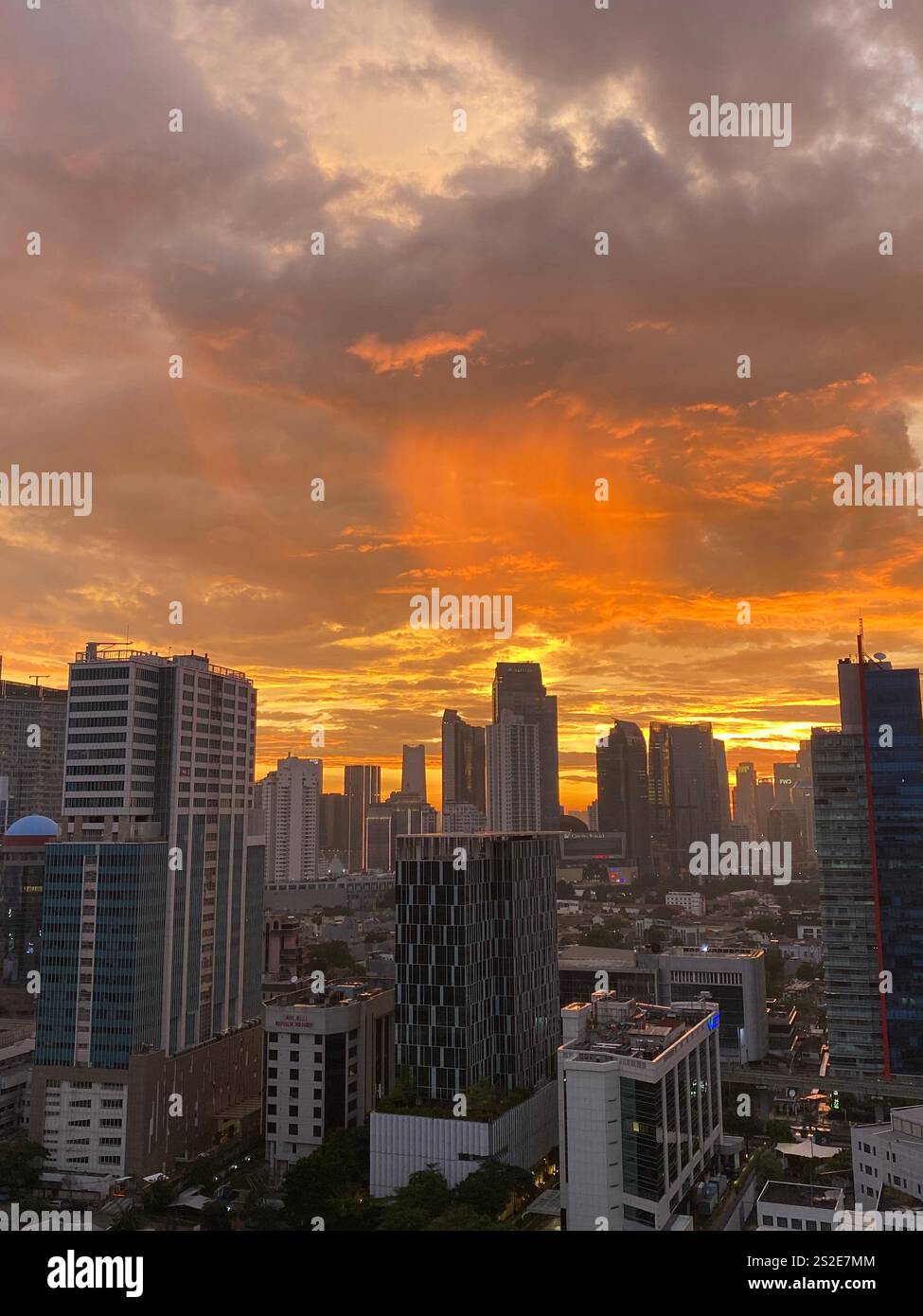 Vibrante tramonto arancione sullo skyline di Giacarta con nuvole spettacolari che creano uno splendido paesaggio urbano Foto Stock