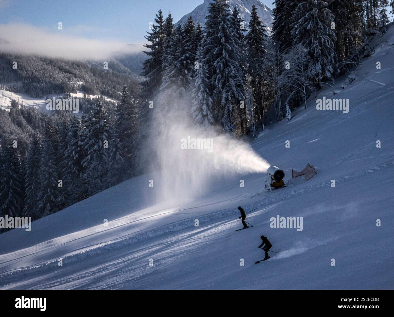 Inverno: Schneekanonen am Hang. - Skifahrer passieren eine Schneekanone, Die künstlichen Schnee auf einem Hang im Skigebiet St. Johann im Pongau Snow S. Foto Stock