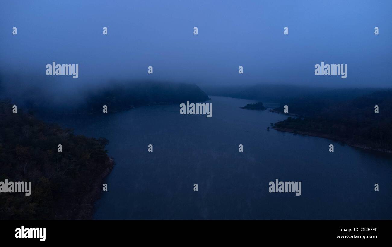 Vista aerea della splendida nebbia sul lago al mattino. Fresco di mattina presto nella foresta vicino al fiume. Splendida alba nella foresta con nebbia. Foto Stock