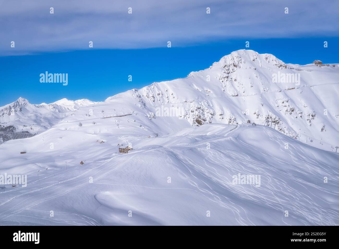 Una vista mozzafiato presenta cime innevate contro un cielo blu, che illustrano la bellezza degli inverni, rendendolo lo sfondo perfetto per sciare ed esplorare Foto Stock