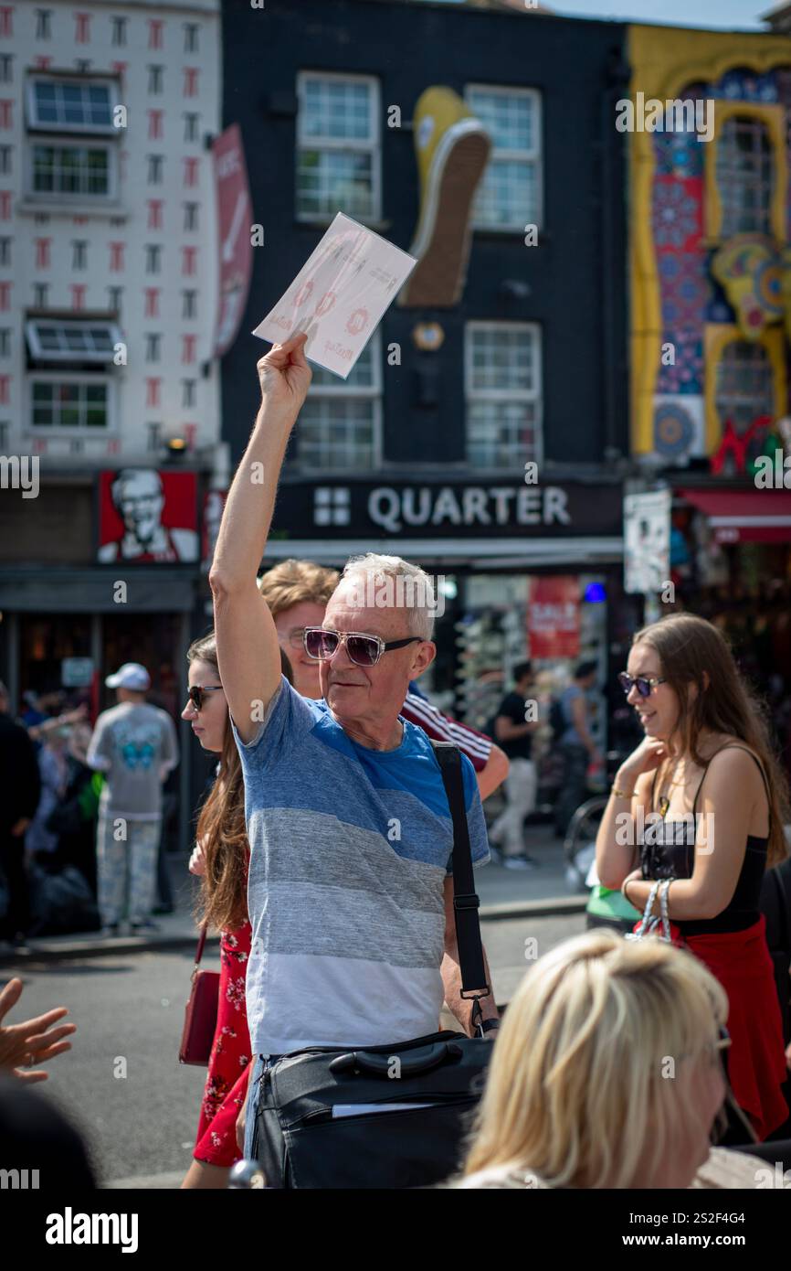 Una guida turistica da Meetup che parla con il gruppo in una strada trafficata di Camden. Foto Stock