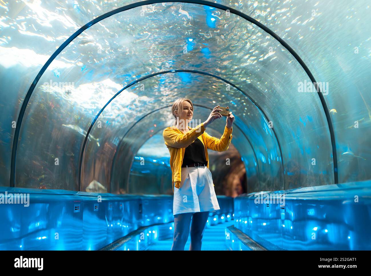 Una donna in un tunnel sottomarino con creature marine. Foto Stock