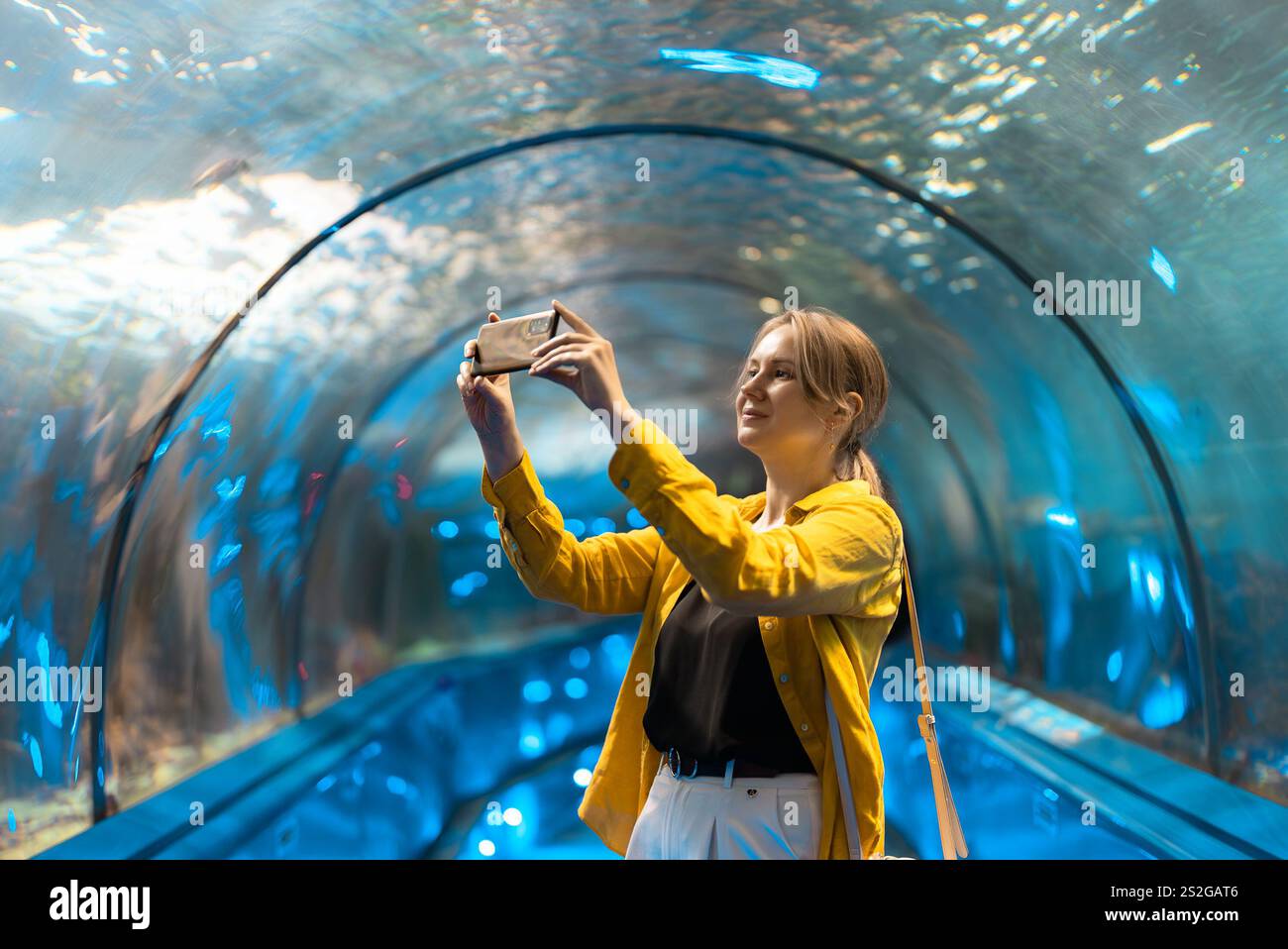 Una donna in un tunnel sottomarino con creature marine. Foto Stock