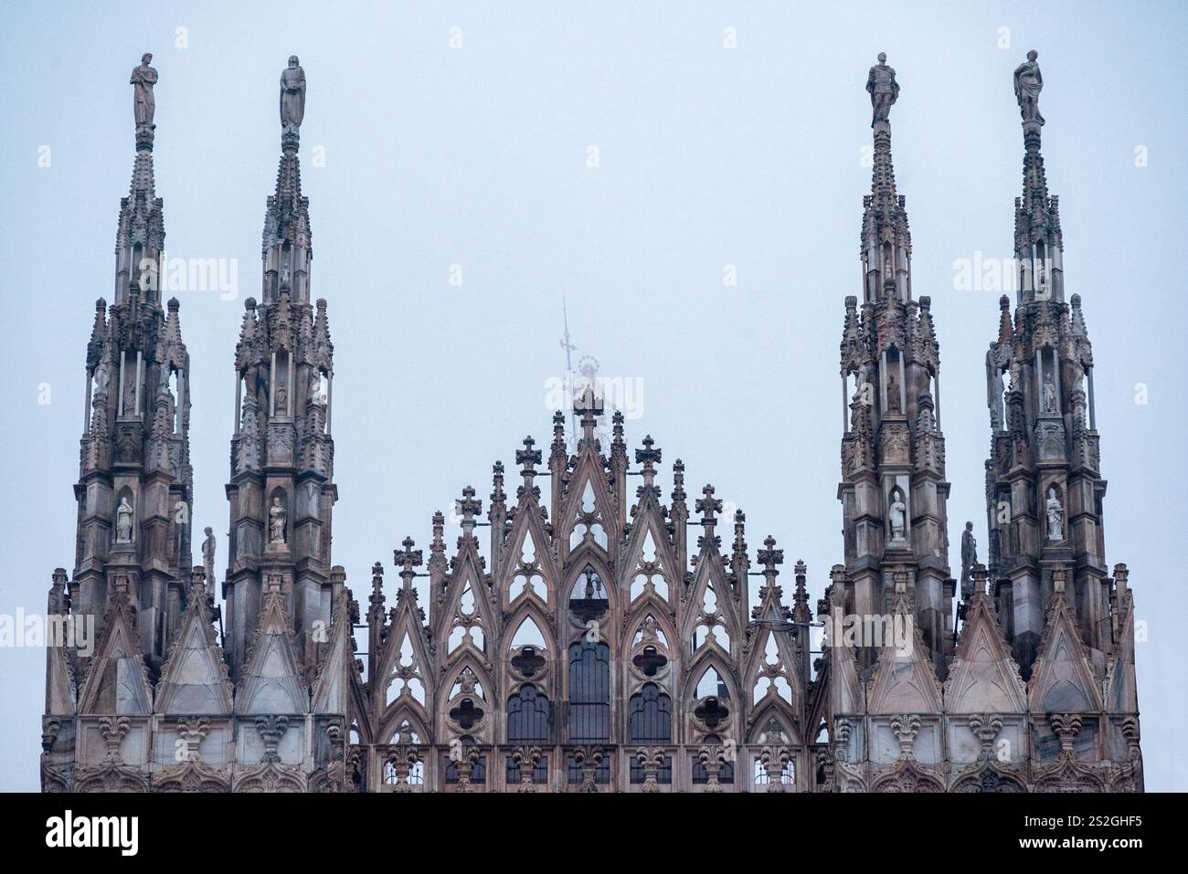 Dettagli e particolari delle statue sulle guglie della facciata del Duomo di Milano. Statuetta della Madonna nella nebbia Foto Stock