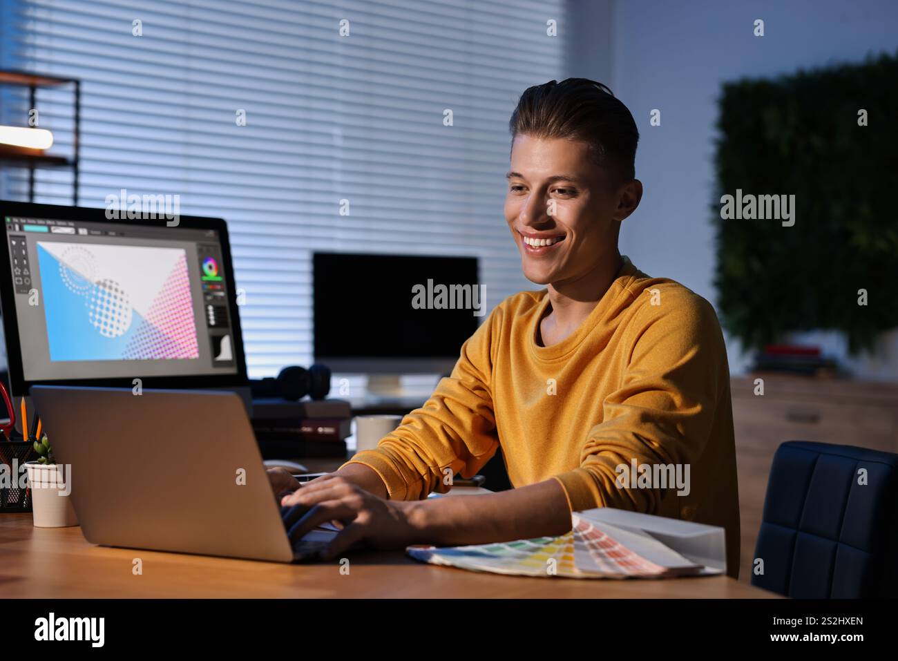 Designer che lavora su un notebook in interni di notte Foto Stock