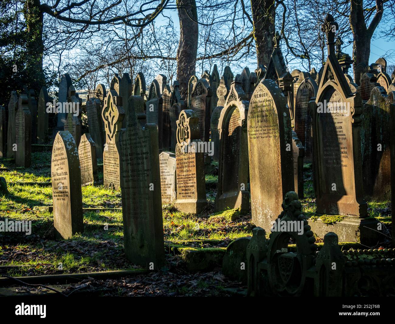 Lapidi nel cimitero illuminato dal sole della chiesa di St Michael All Angels a Haworth, Bronte Country, West Yorkshire. REGNO UNITO Foto Stock