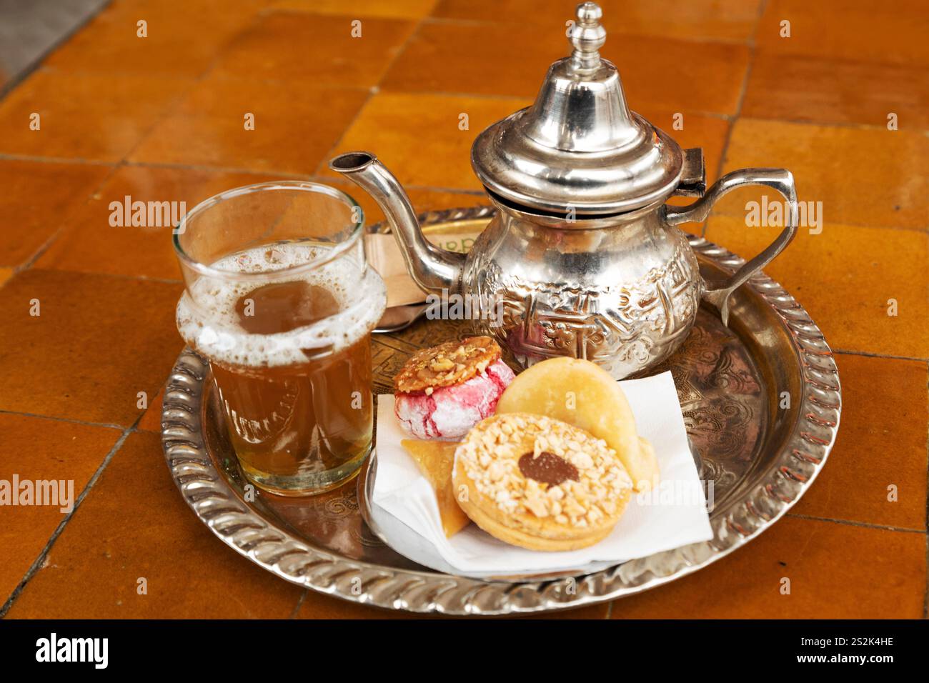 Tè alla menta servito a Marrakech, Marocco. La bevanda è una bevanda popolare in Marocco ed è servita qui con prodotti di pasticceria. Foto Stock