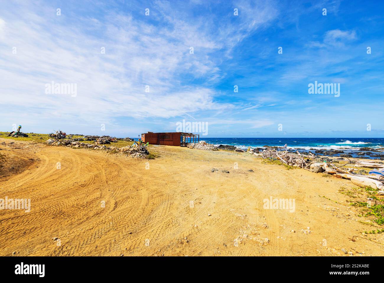 Paesaggio costiero desertico con rustico riparo in legno che si affaccia sul Mar dei Caraibi sotto un cielo blu brillante. Aruba. Foto Stock