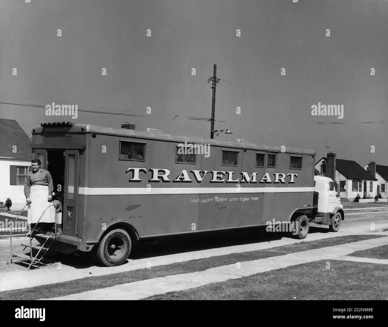 Il Travel Mart, un supermercato su ruote che serve piccole comunità suburbane, erano centri commerciali nei quartieri periferici. Aiuta la casalinga portando le provviste di cibo direttamente alla sua porta. Vista laterale del carrello che mostra il proprietario alla porta. Foto Stock