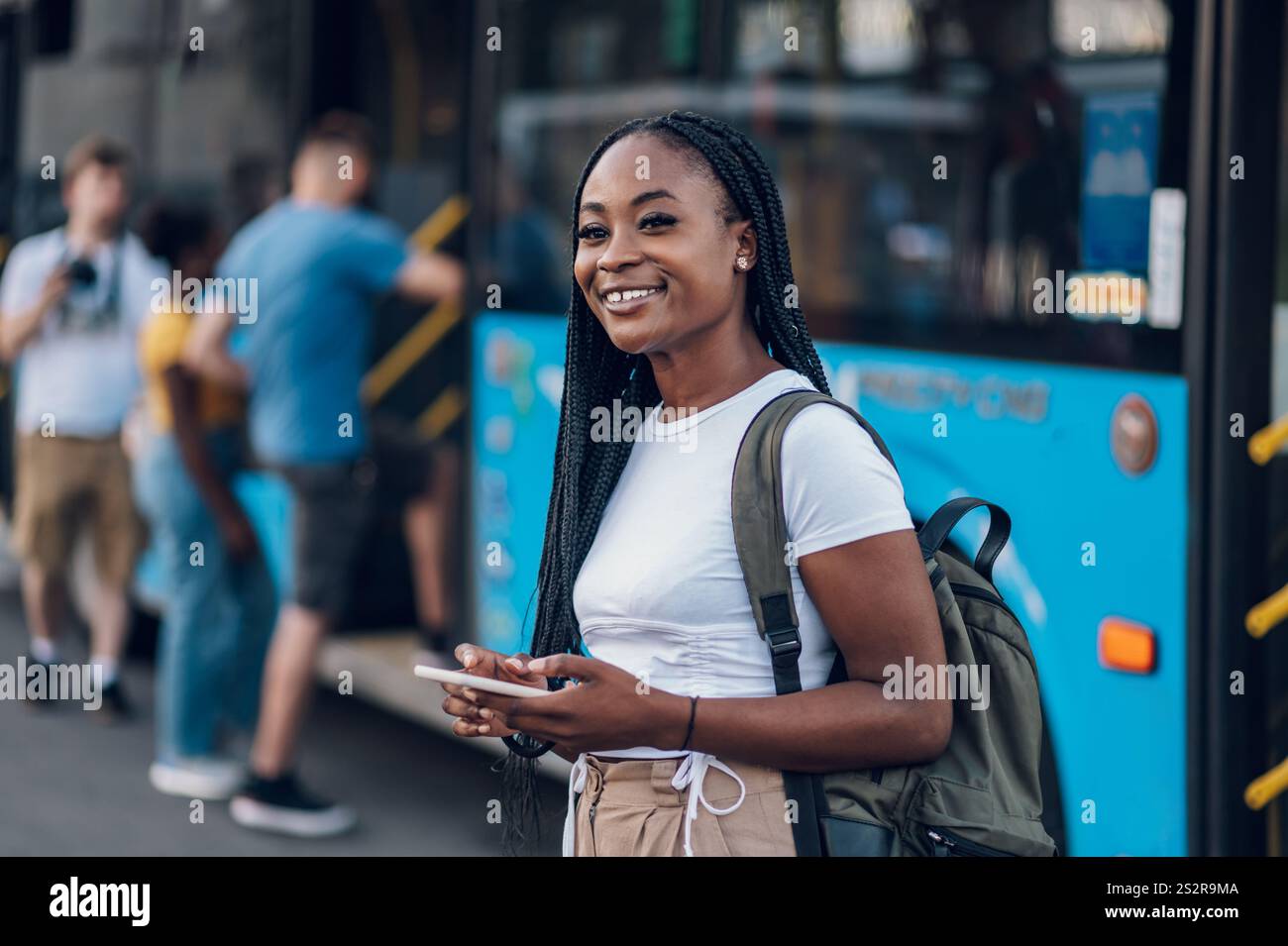 Un'attraente donna afroamericana che aspetta un autobus mentre va a scuola o al lavoro. Ritratto di una bella donna nera che usa i mezzi pubblici Foto Stock