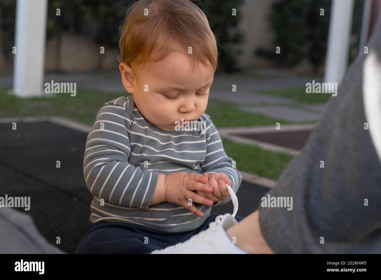 Il bambino sviluppa la pinza afferrando il lacci delle scarpe Foto Stock
