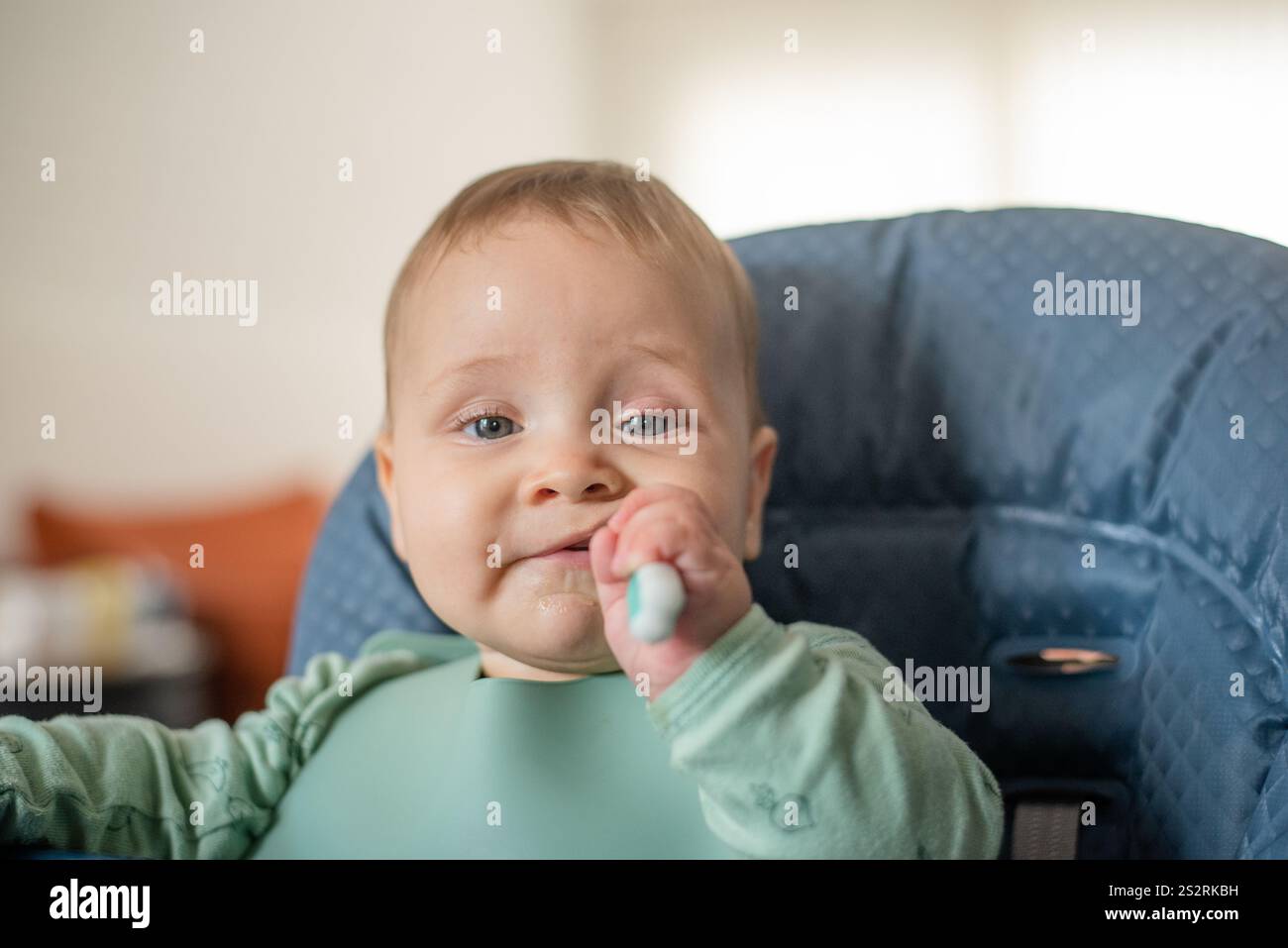 bimbo di 6 mesi che inizia a nutrire cibi solidi usando il cucchiaio da addestramento Foto Stock