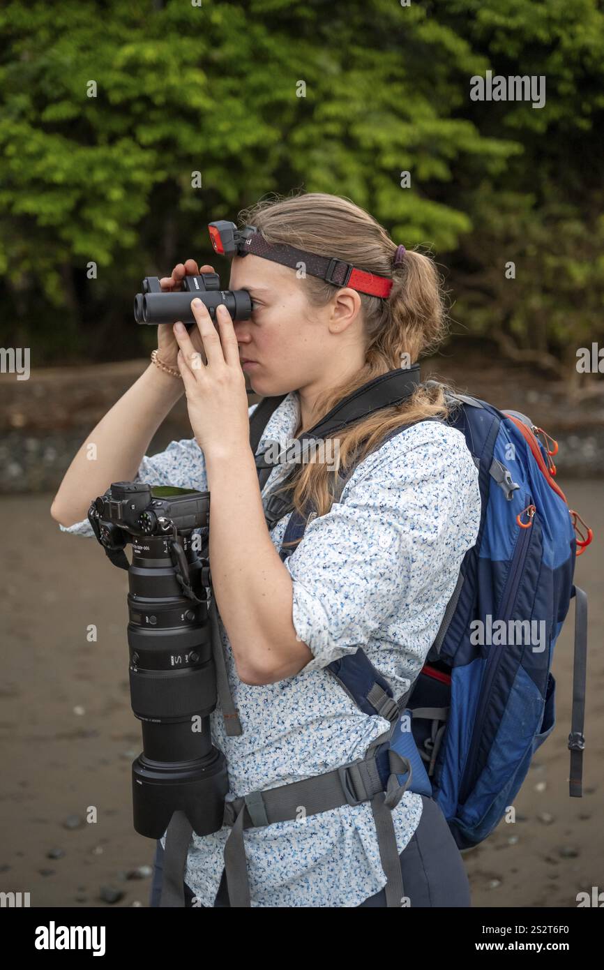 Turisti che guardano attraverso binocoli, con faro e fotocamera nella foresta pluviale, Parco Nazionale del Corcovado, Penisola di osa, Provincia di Puntarena, Costa Rica Foto Stock