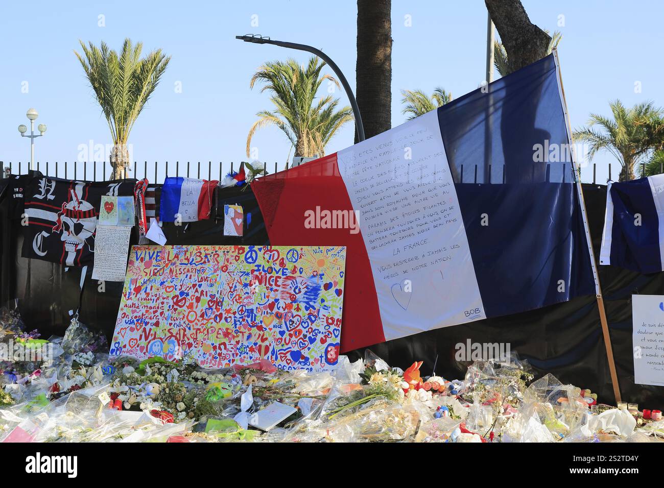 Fiori deposti, bandiera nazionale francese sulla Promenade des Anglais dopo l'attacco del 14 luglio 2016 in cui l'aggressore Mohamed Bouhlel guidò uno lo Foto Stock