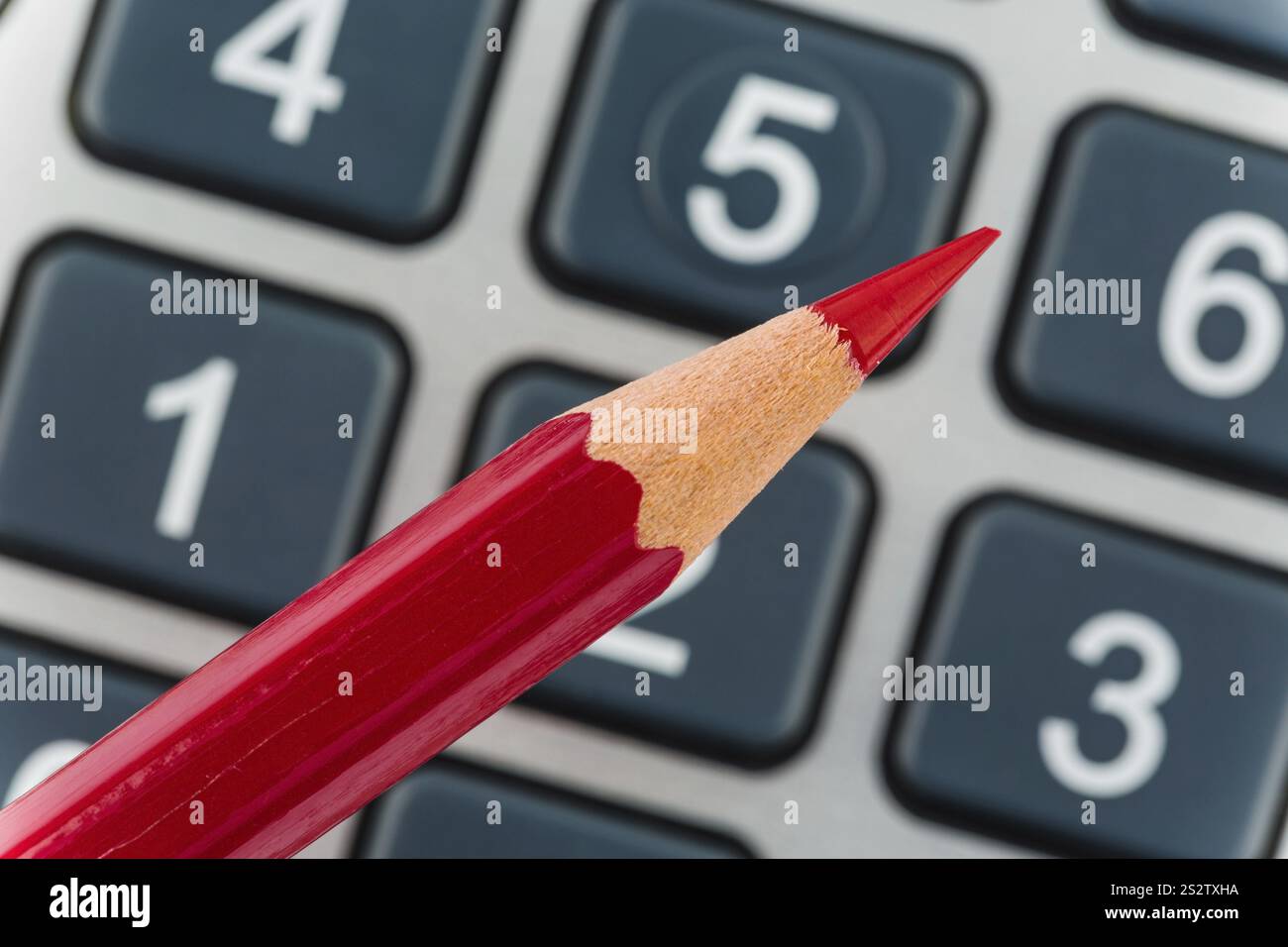 Una penna rossa giace su una calcolatrice tascabile. Risparmio su costi, spese e budget a causa della scarsa situazione economica Austria Foto Stock