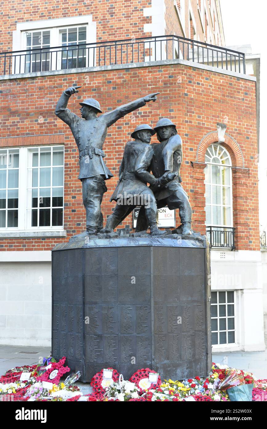 National Firefighters Memorial Blitz 1990 di John William Mills, vicino alla cattedrale di St Paul, Londra, Un monumento con statue di soldati e fiori Foto Stock