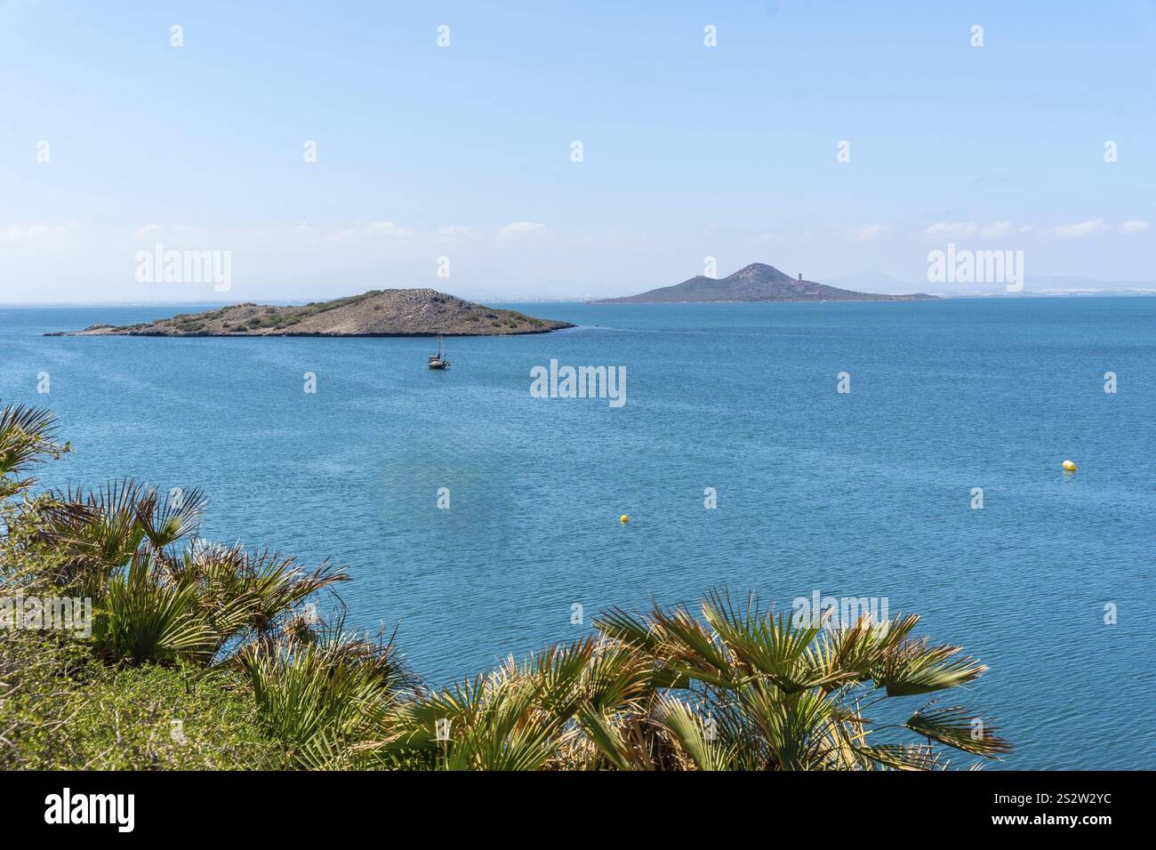 Tranquillo paesaggio marino di la manga del mar menor che mostra una barca a vela che naviga nelle acque calme tra l'isola grosa e la terraferma Foto Stock