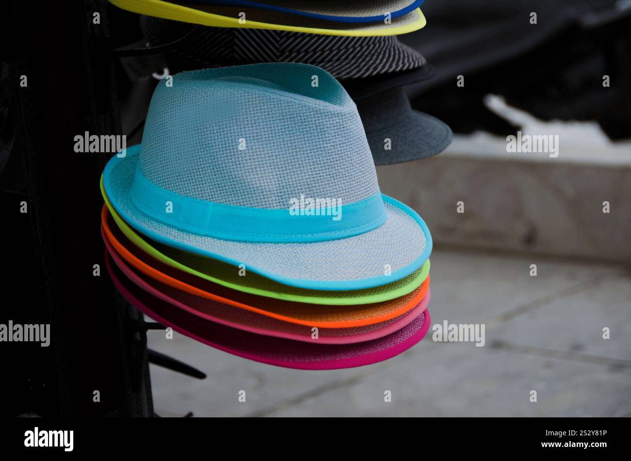 Cappelli colorati in un negozio all'aperto impilati in una fila. Vari cappelli moda vetrina negozio. Foto Stock