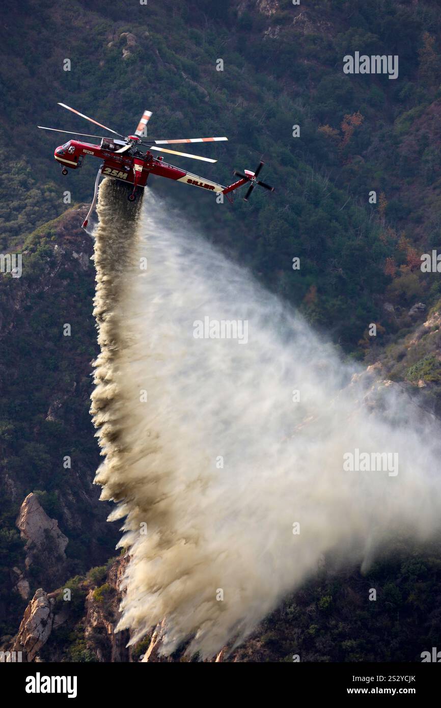 LOS ANGELES COUNTY, CALIFORNIA, USA - 13 dicembre 2024 - Un elicottero antincendio specializzato getta l'acqua su un canyon nella contea di Los Angeles, Californi Foto Stock