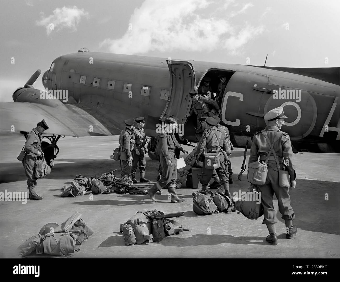 Le truppe britanniche sbarcano da una portatruppe Douglas Dakota DC-3. Un monoplano in metallo ad ala bassa con carrello di atterraggio convenzionale, alimentato da due motori radiali a pistoni, era veloce, con una buona portata, affidabile e poteva funzionare da brevi piste. Durante la seconda guerra mondiale, furono costruite più di 10.000 versioni militari statunitensi del DC-3, con le forze armate di molti paesi che usavano il DC-3 e le sue varianti militari per il trasporto di truppe, merci e feriti Foto Stock