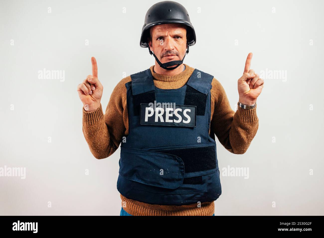 Reporter in giubbotto antiproiettile che punta verso il cielo. Foto Stock