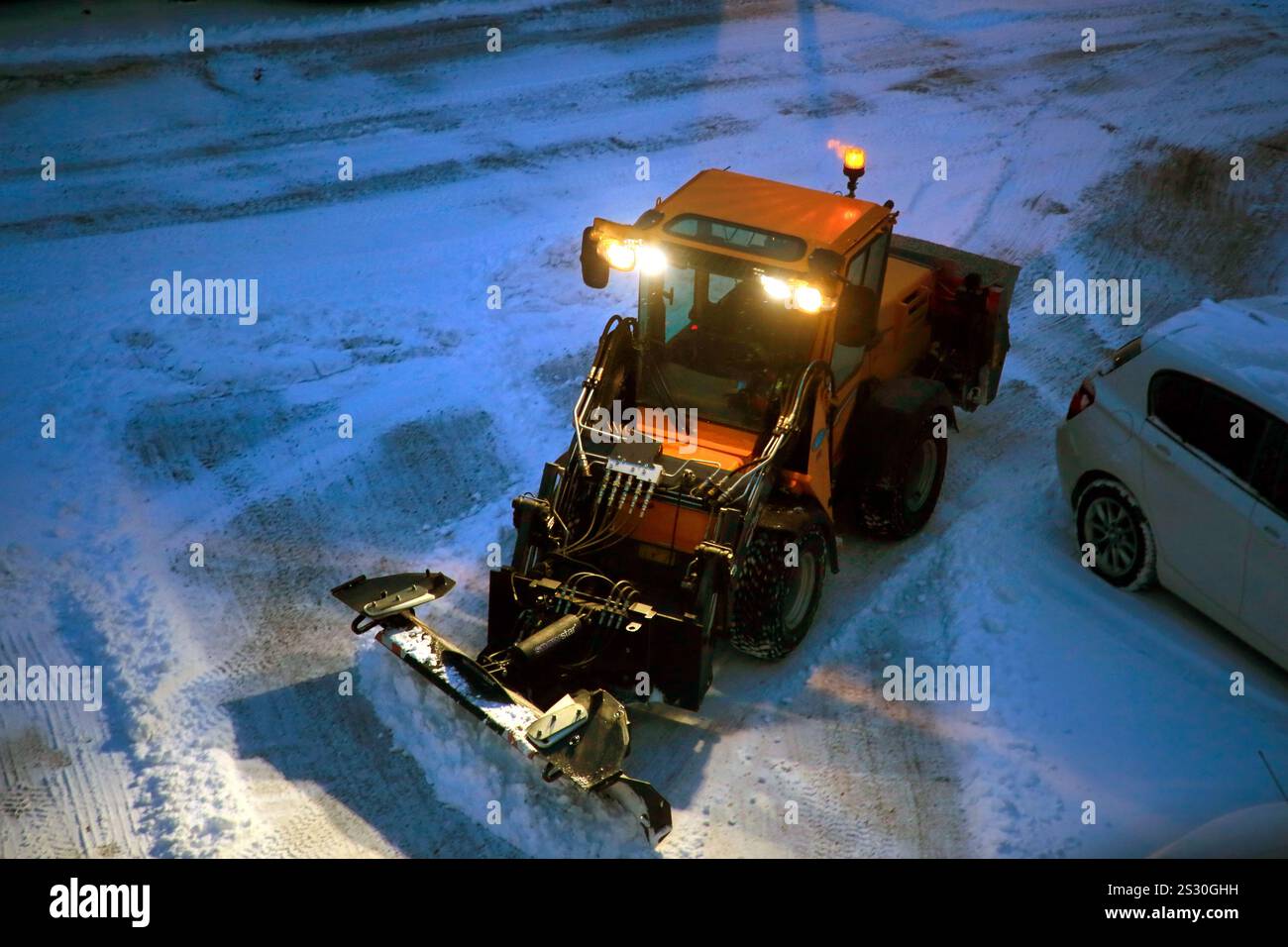 Rimozione della neve con il trattore multiuso compatto Wille 365 dotato di spazzaneve Snowstar e gritter nell'area di parcheggio. Salo, Finlandia. 1° gennaio 2025. Foto Stock