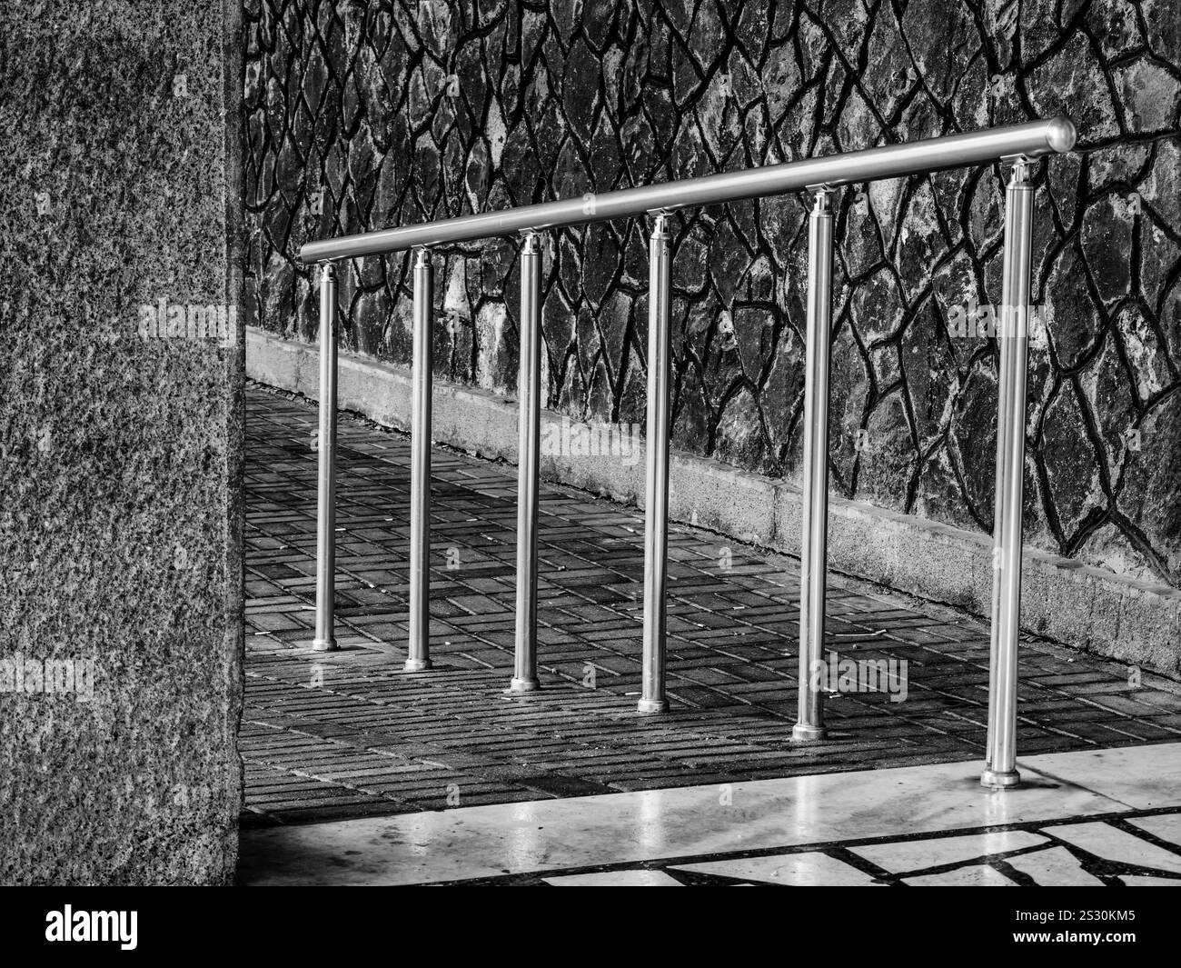 Silver Handrail Fence, dietro l'angolo. Sfondo da parete in pietra. Foto Stock