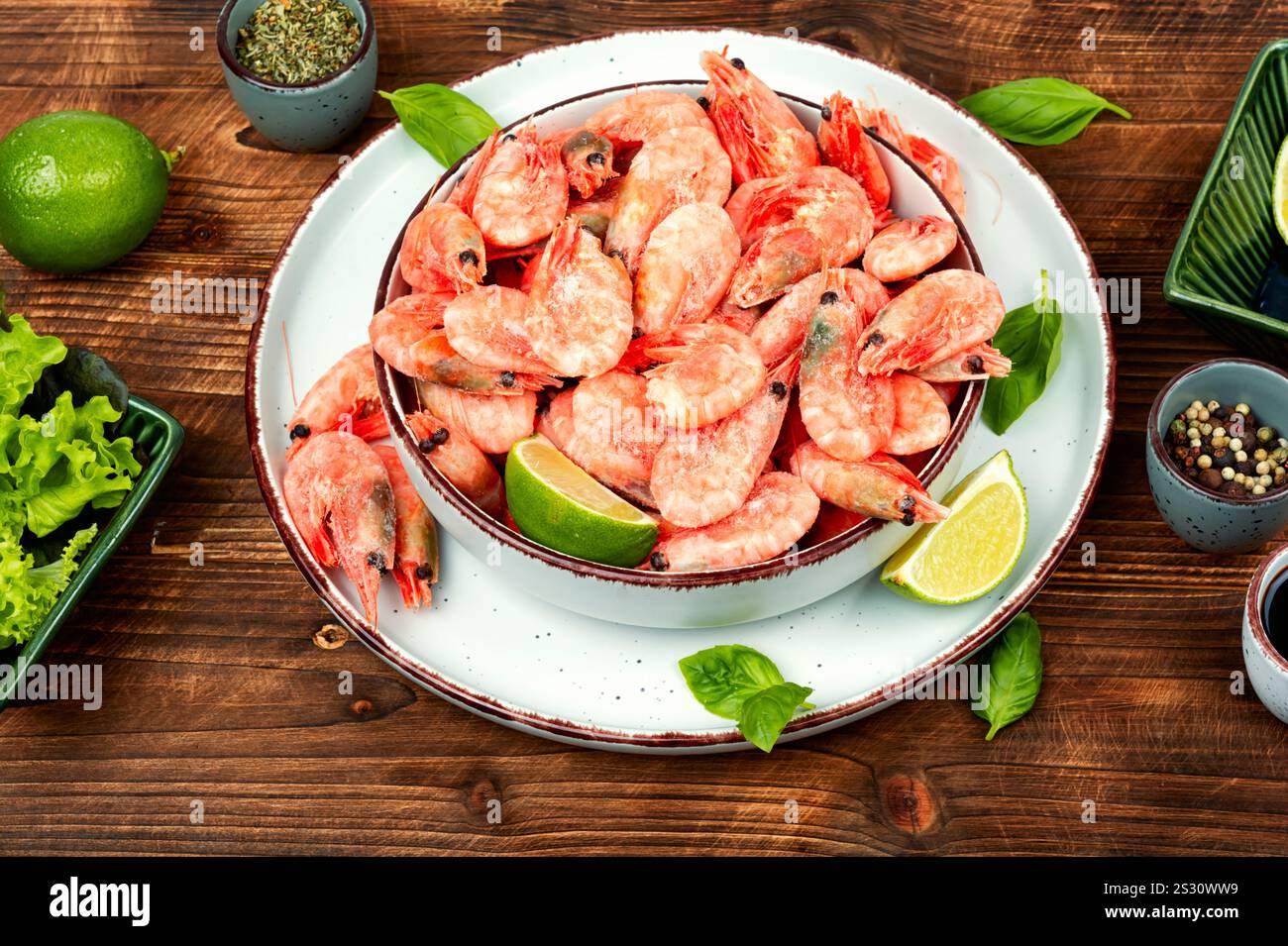 Deliziosi gamberi crudi non sbucciati o gamberetti con spezie ed erbe aromatiche su una tavola rustica in legno. Cibo sano. Foto Stock