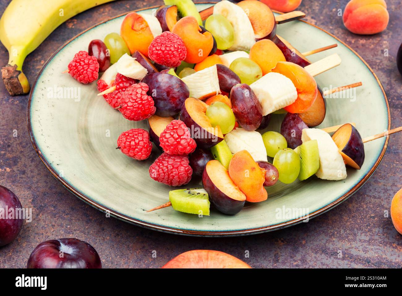 Gustosi spiedini di frutta fresca su spiedini di legno. Frutta esotica mista su spiedini Foto Stock
