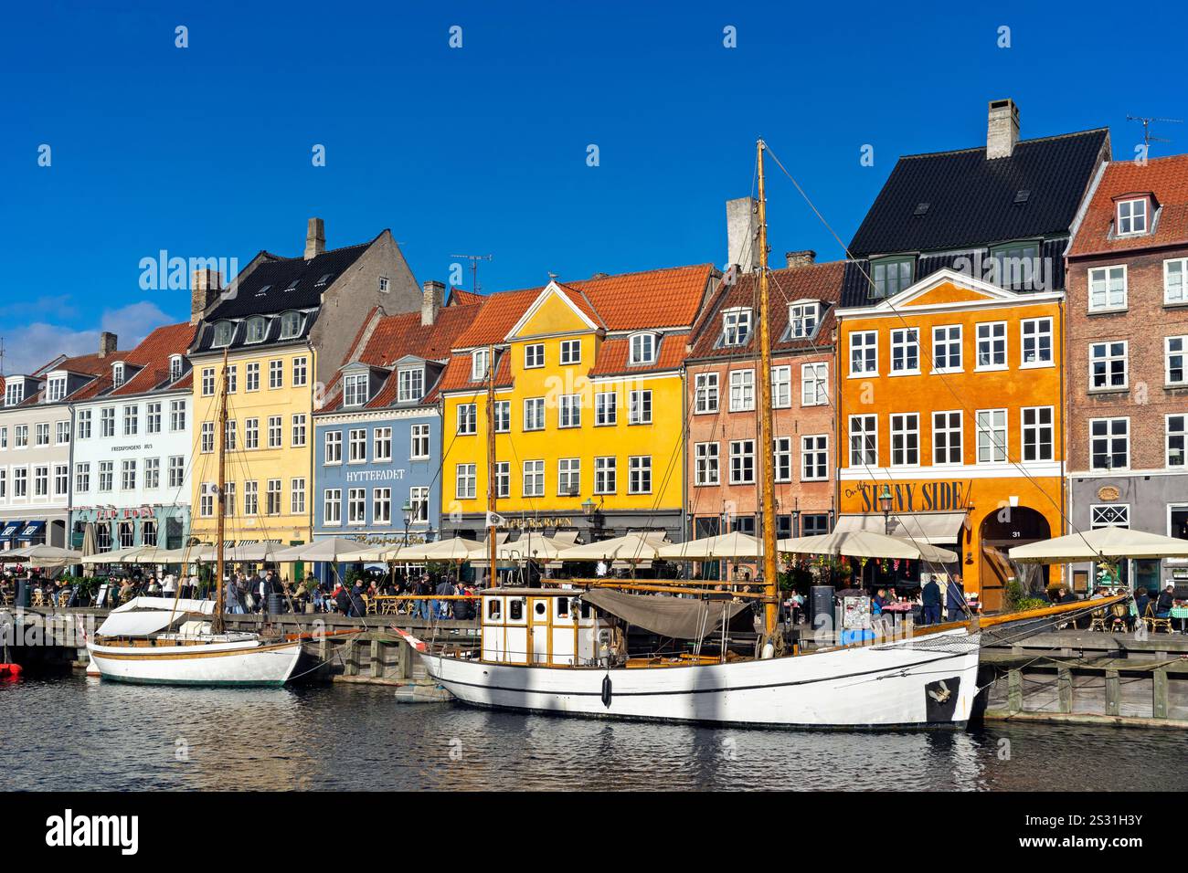 Edifici colorati e barche attraccate a Nyhavn, Copenhagen, Danimarca, in una giornata di sole con un cielo azzurro. Foto Stock