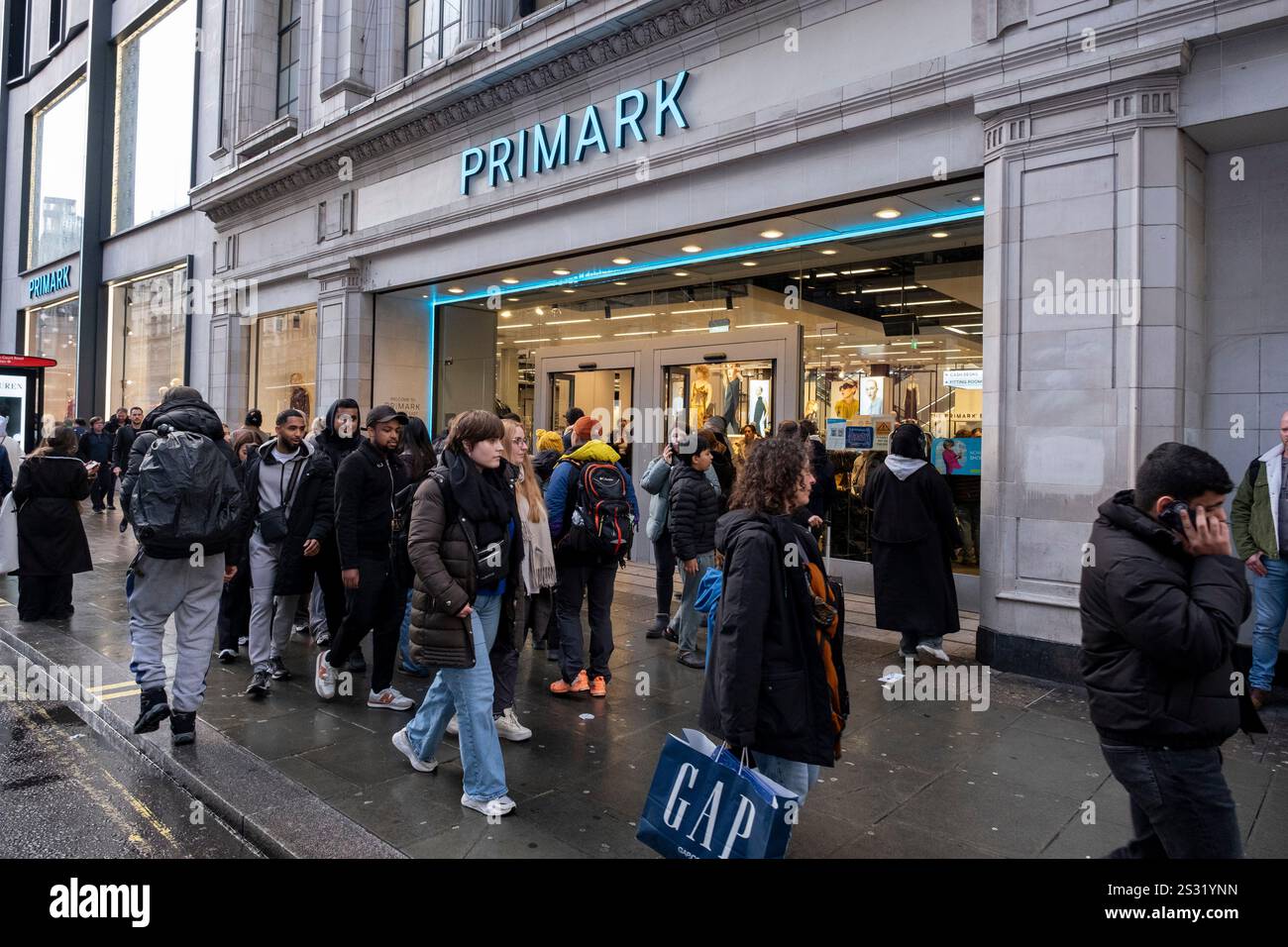 Acquirenti e visitatori fuori su Oxford Street fuori Primark il 1 dicembre 2024 a Londra, Regno Unito. Oxford Street è un importante centro commerciale nel West End della capitale ed è la strada commerciale più trafficata d'Europa, con circa mezzo milione di visitatori al giorno ai suoi circa 300 negozi, la maggior parte dei quali sono negozi di moda e di abbigliamento di alta moda. Foto Stock