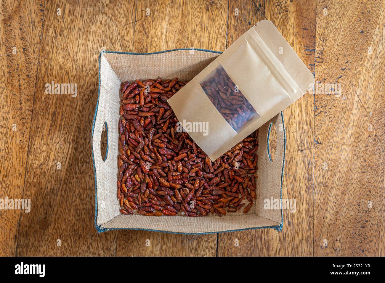 Madagascar Island gastronomia natura morta. Un cestino e una borsa riempiti di peperoncino posti su un tavolo di legno Foto Stock