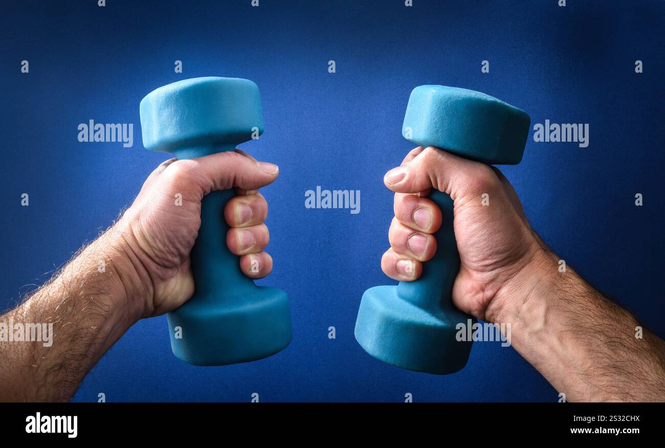 Dettaglio delle braccia dell'uomo forte che sollevano manubri in neoprene blu isolati su sfondo blu gradiente. Foto Stock