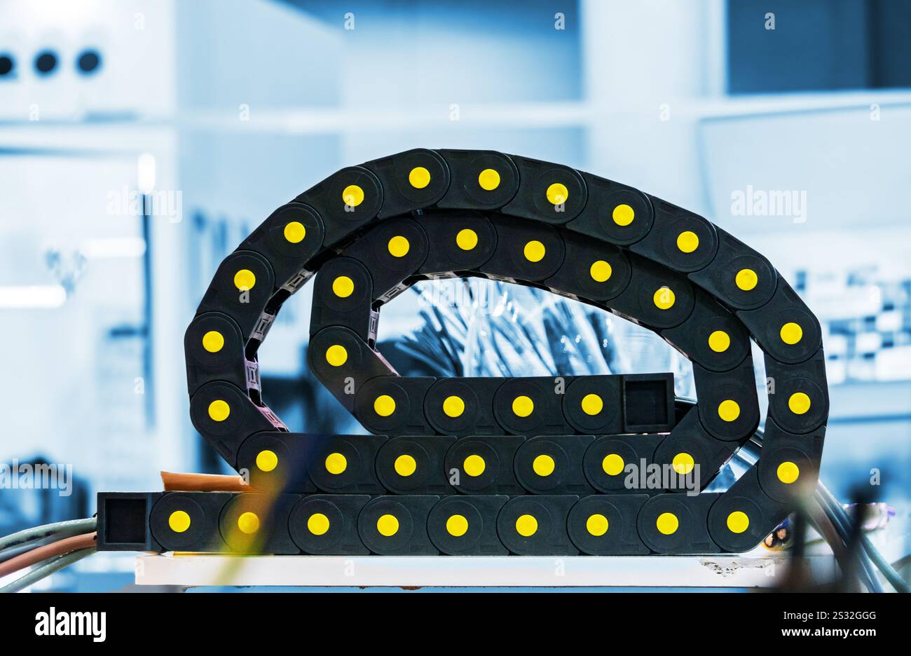 Una catena portacavi nera, una catena portacavi, progettata per le applicazioni industriali. Il supporto è costituito da segmenti modulari in plastica interconnessi con brillanti Foto Stock