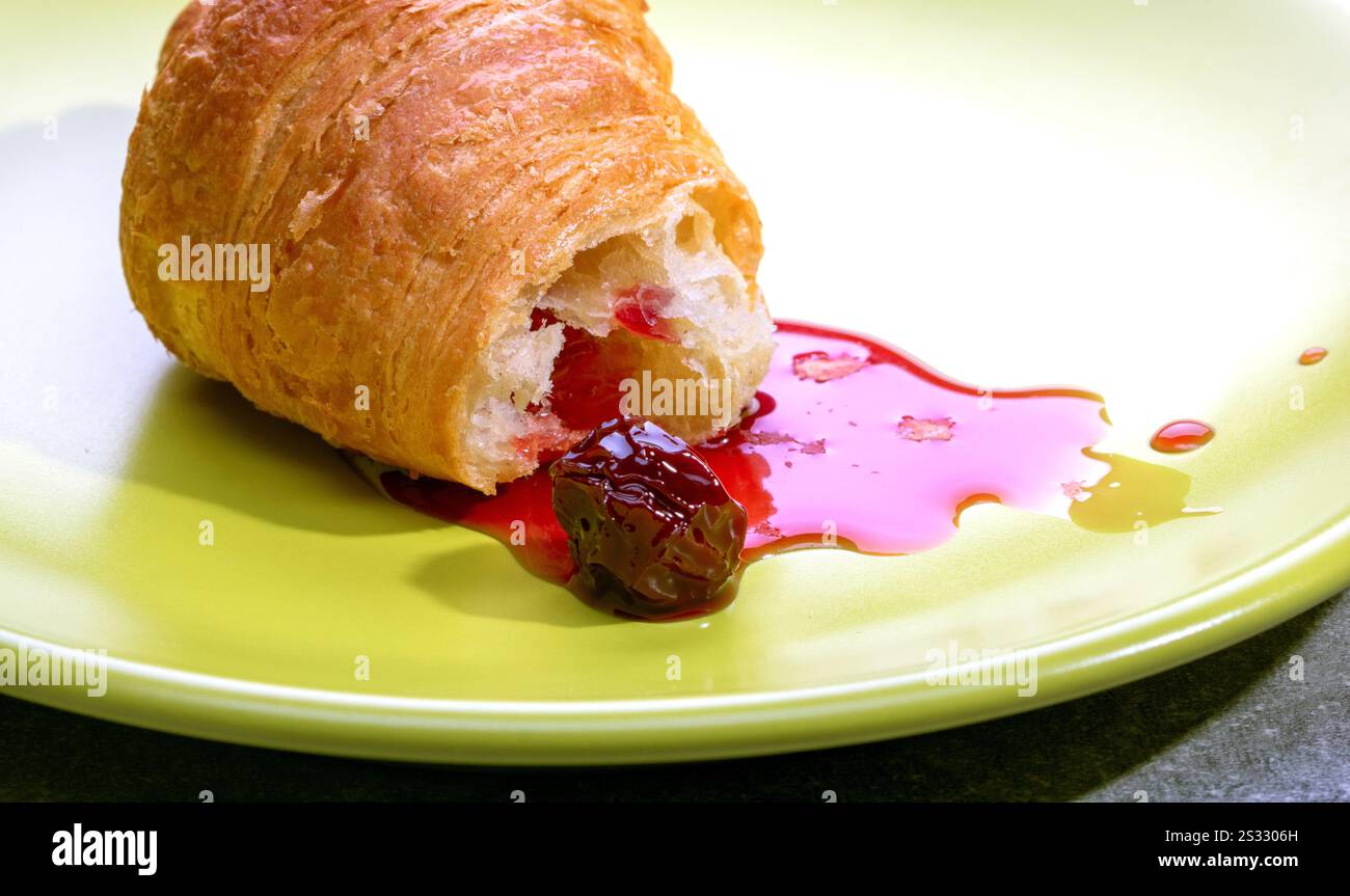 Croissant con marmellata di ciliegie su un piatto. Foto Stock