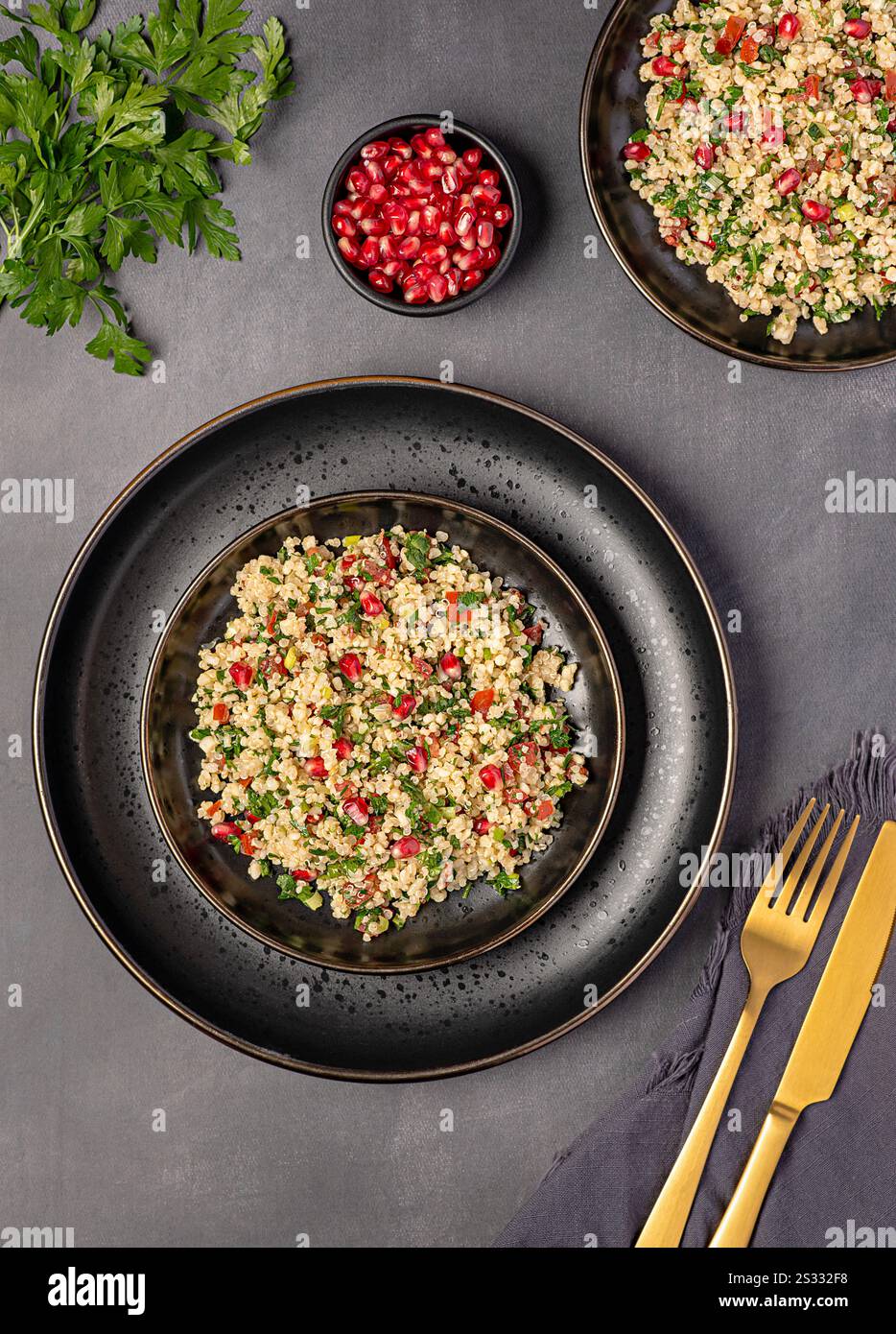 Fotografia gastronomica di tabouleh di insalata con melograno, bulgur; prezzemolo, menta, pomodoro, cipolla primaverile, piatto vegano, cibo arabo Foto Stock