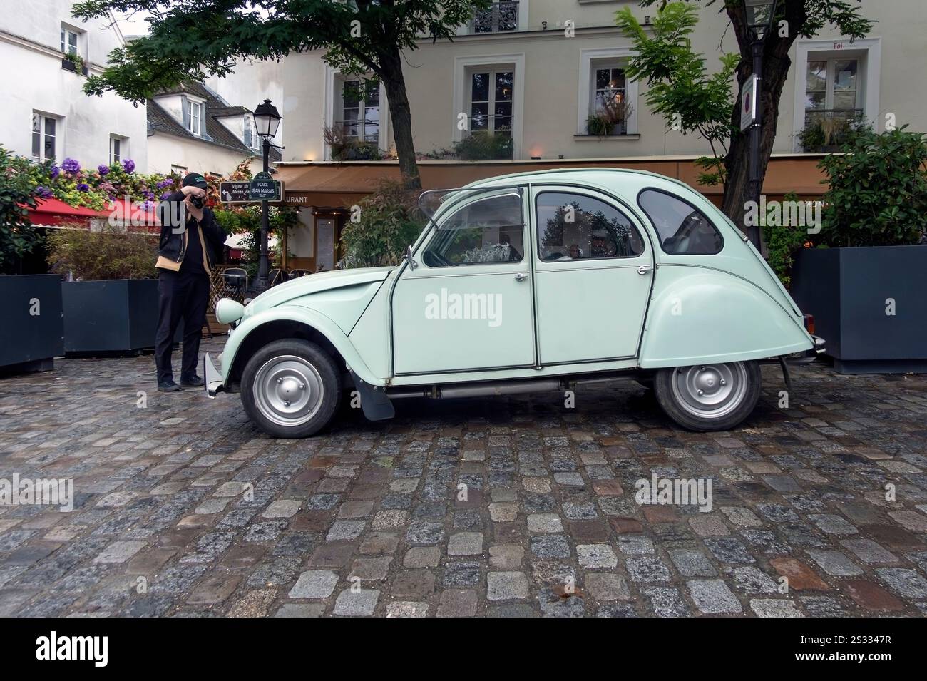 L'uomo fotografa l'auto Citroen 2CV in Place de Jean Marais, Montmartre, Parigi, Francia Foto Stock