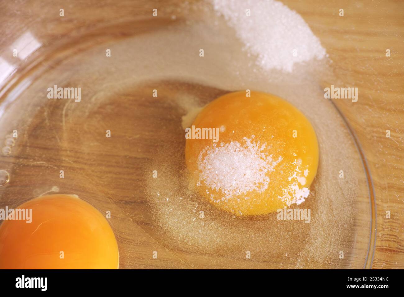 Uova con zucchero pronte per essere montate all'interno di un recipiente di vetro. Primo piano. Foto Stock