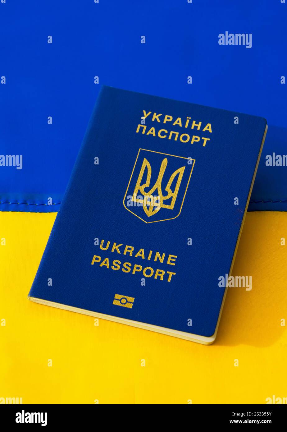 Passaporto ucraino sullo sfondo della bandiera Ucraina. Migrazione del popolo ucraino in relazione all'invasione delle truppe russe. Foto Stock