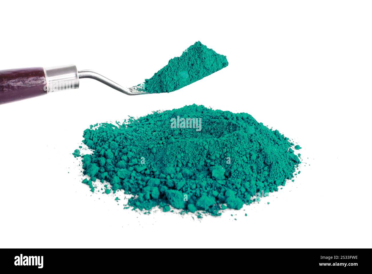 Pigmento verde brillante impilato accanto a una paletta su sfondo bianco Foto Stock