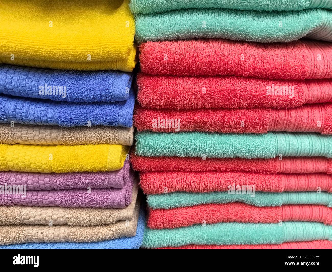 I colori si fondono magnificamente, mentre vari asciugamani sono impilati meticolosamente, mostrando una tavolozza di gialli, blu, rosa e verdi. Le fibre morbide suggeriscono un Foto Stock