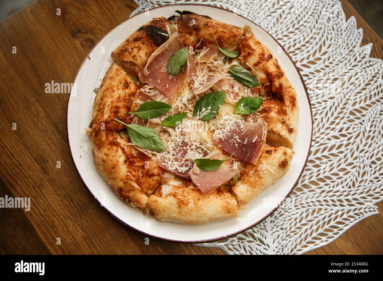 Deliziosa pizza completa con prosciutto servita sul tavolo del ristorante all'aperto, foto ravvicinate della cucina italiana su un piatto all'aperto, fuori, nessuno Foto Stock