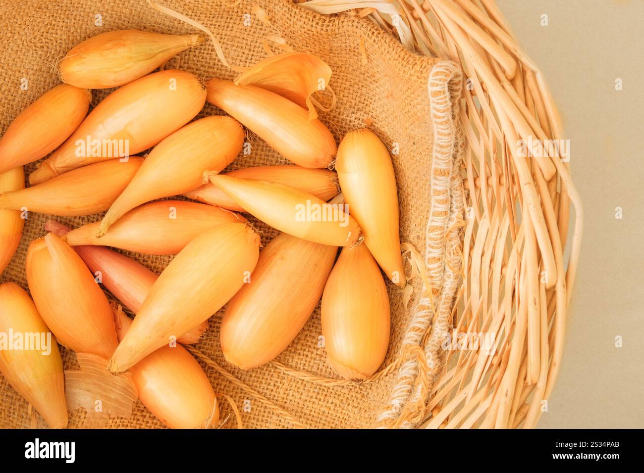 Scalogni in un cestello di paglia. Cipolla matura arancione. Verdure dall'odore e dal sapore forti. Vista dall'alto. Posiziona per testo. Foto Stock