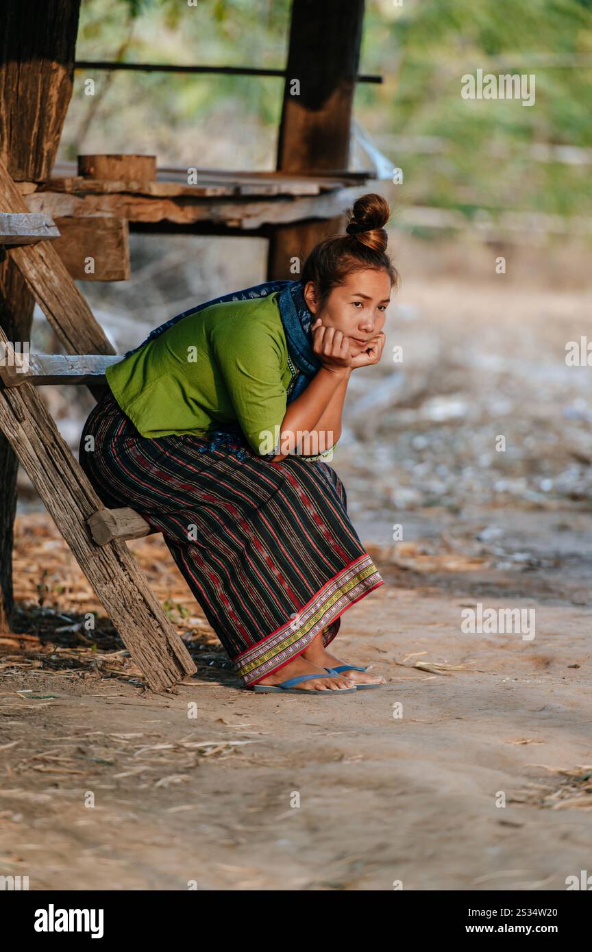 Bella donna asiatica seduta su una scala di legno e sul mento a portata di mano, guarda avanti con sentirsi sola, spazio copia, concetto di stile di vita raro Foto Stock