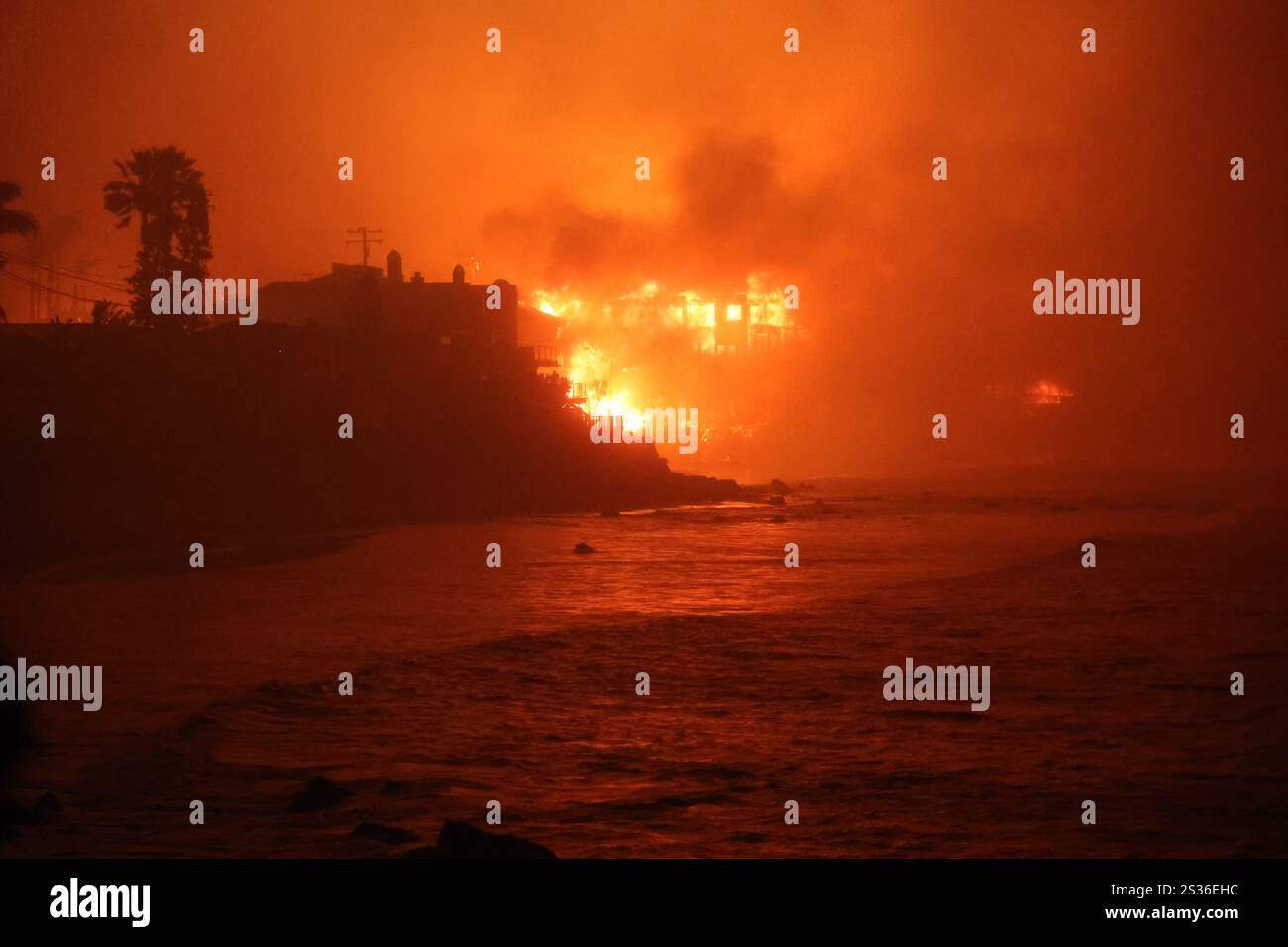 Una casa fiammeggiante sulla costa, che mette in evidenza l'intensa devastazione causata dall'incendio di Palisades lungo la Pacific Coast Highway l'8 gennaio 2025 a Los Angeles, California. (Foto di CAL FIRE) Foto Stock